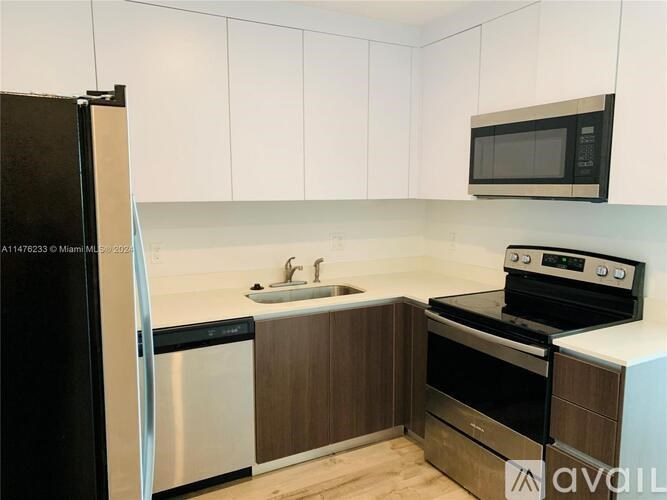 A kitchen with a black fridge, a black stove, a white sink and wooden cabinets.