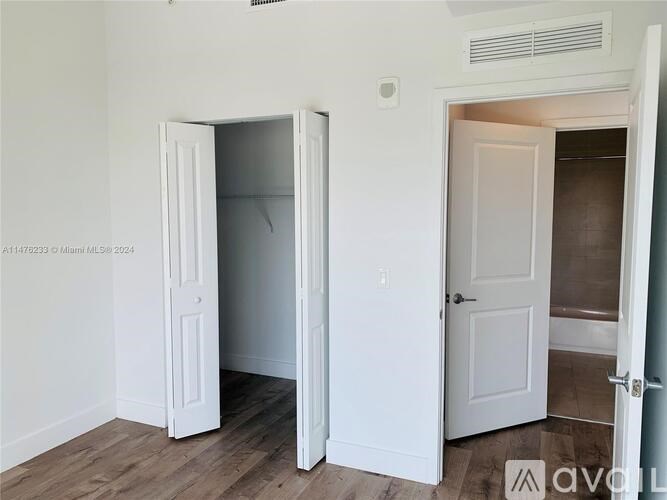A room with two open doors and a wooden floor.