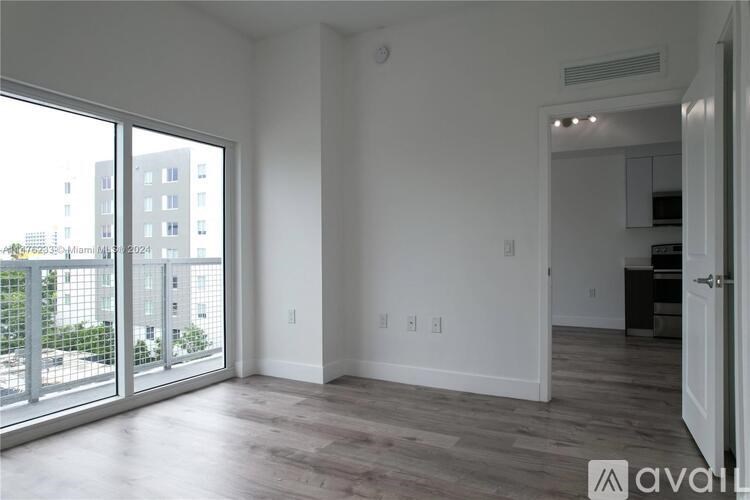 A spacious living room with a sliding glass door leading to a balcony.