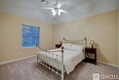 A bedroom with a white bed and a ceiling fan.