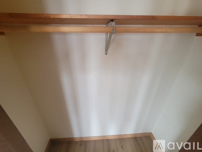 A wooden beam with a metal bracket is mounted on a white wall.