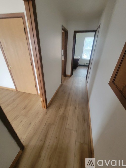 A hallway with wooden floors and white walls.