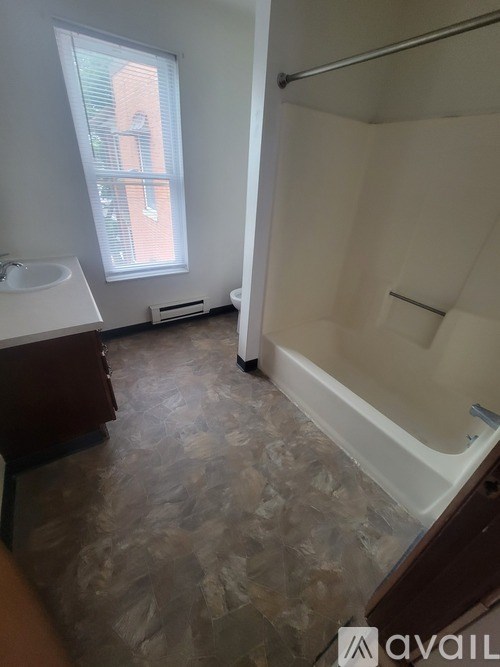 A bathroom with a tub, sink, and window.