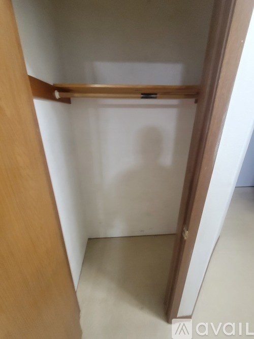 A wooden shelf with a metal bar on top is mounted on a white wall.