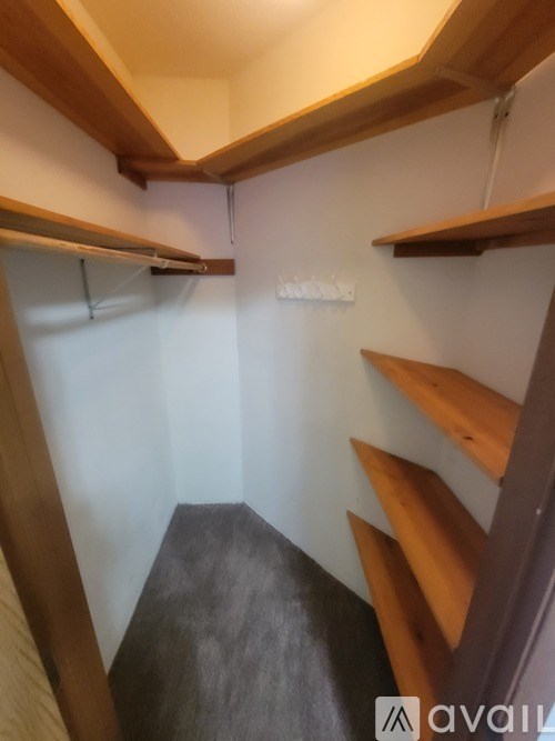 A small room with wooden shelves and a grey carpet.