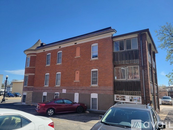 A red car is parked in front of a red brick building.