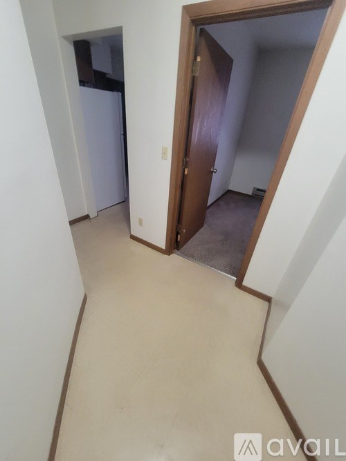 A room with a white fridge and a brown door.