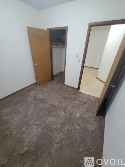 A room with a carpeted floor and a wooden door.