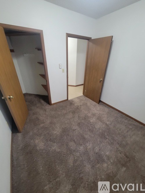 A room with a carpeted floor and two wooden doors.