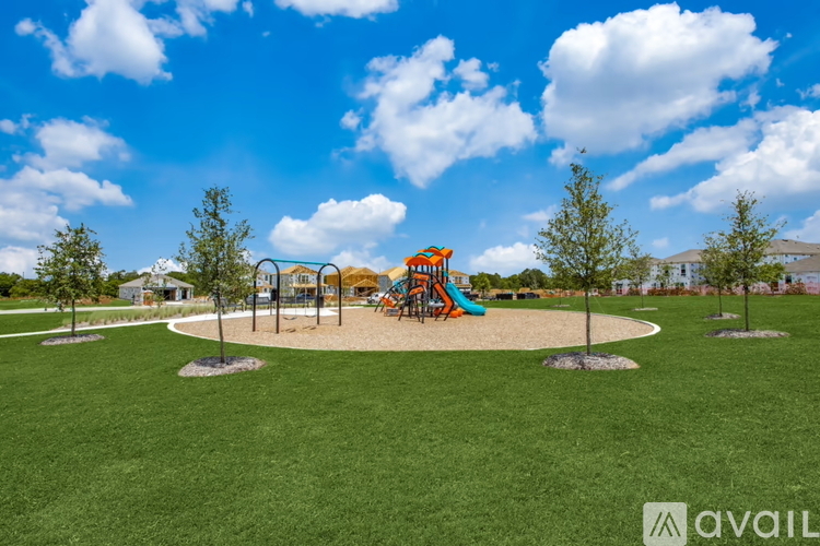 A playground with a slide and swings in the middle of a grassy area.