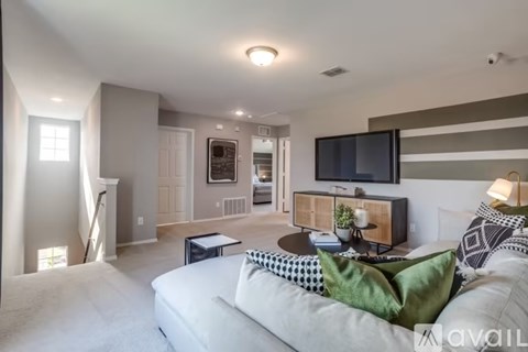 A living room with a white couch and a television mounted on the wall.
