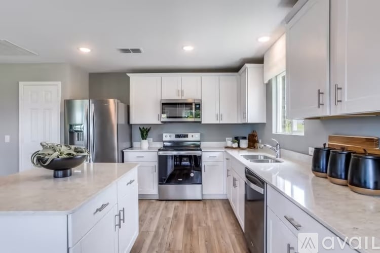 A modern kitchen with white cabinets and stainless steel appliances.