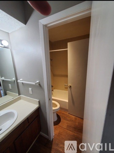 A bathroom with a toilet, sink, and mirror.