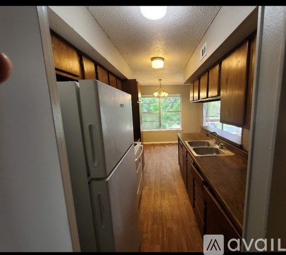 A kitchen with a refrigerator, sink, and wooden cabinets.