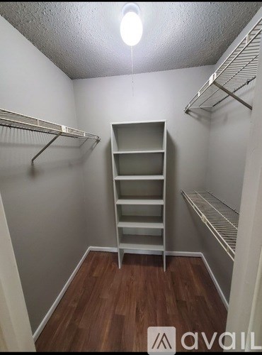 A small walk-in closet with a shelving unit and two racks of clothes.