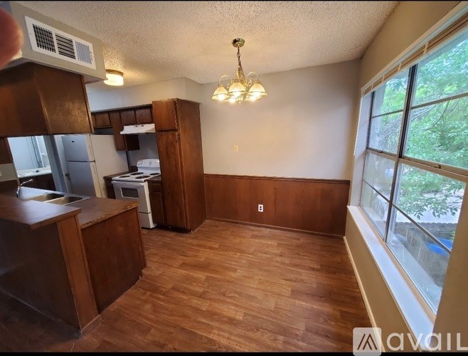 A kitchen with wooden floors and a window with a view of trees.