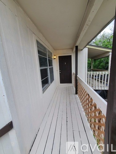 A white wooden deck with a black door and a small balcony.