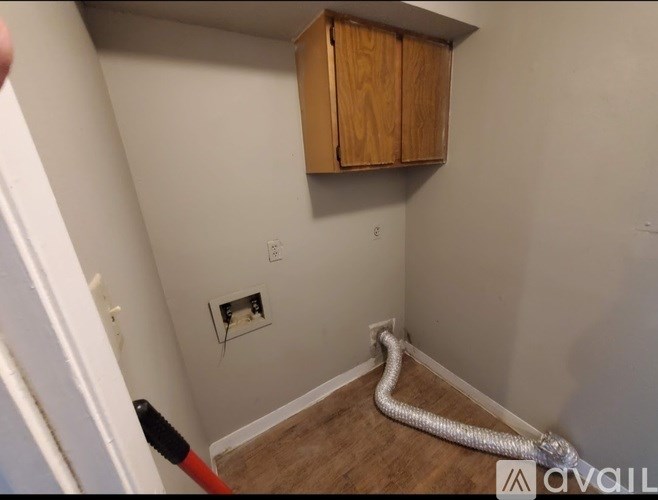 A room with a white wall and a wooden cabinet.