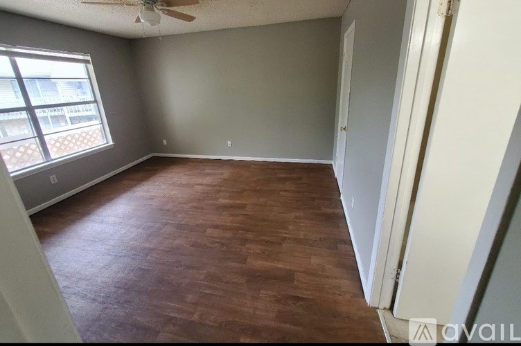 A room with wooden flooring and a window with a view of a building outside.