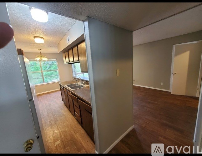 A kitchen with wooden floors and a refrigerator on the left.