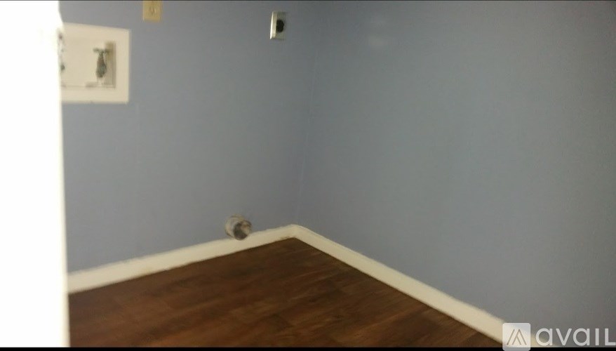 A room with a wooden floor and a wall socket.