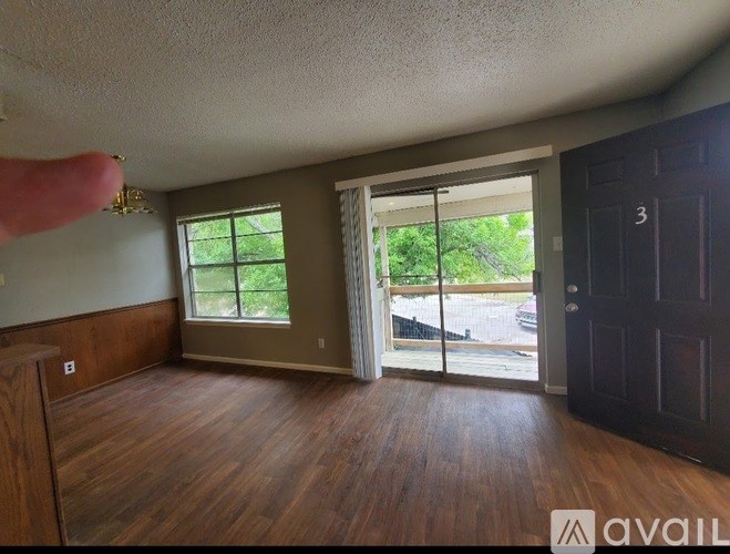A room with wood flooring and a sliding glass door leading to a patio.