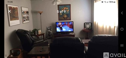 A living room with a television on, a sofa and a chair.