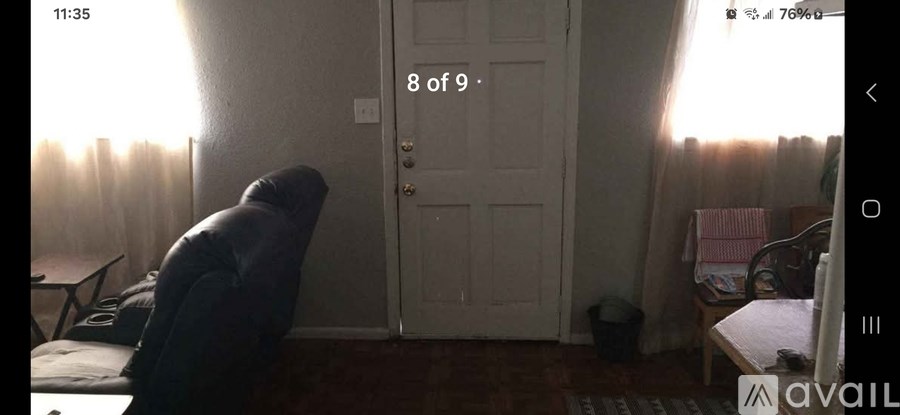 A room with a door, a table, a chair, and a window with curtains.