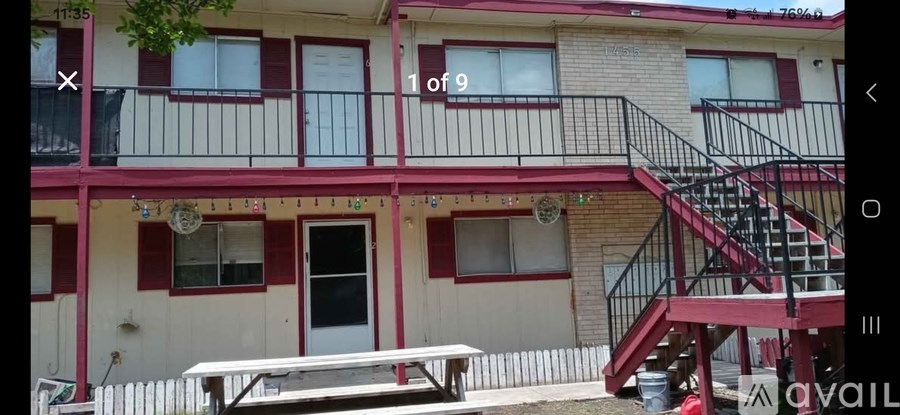 A building with a red and white facade has a balcony and a staircase.