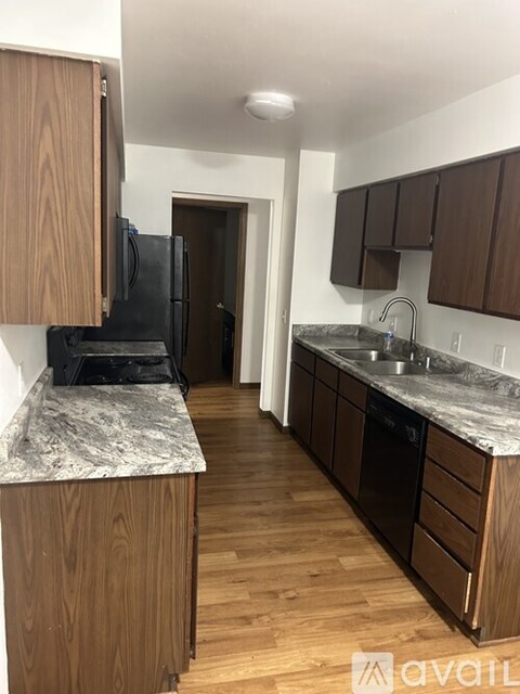 A kitchen with wooden cabinets and a black fridge.