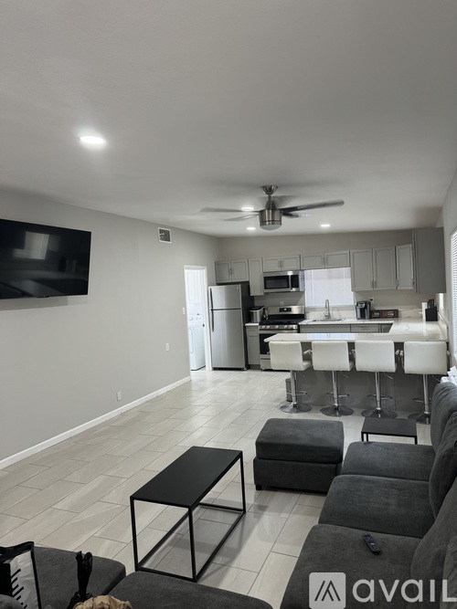 A living room with a black and white color scheme and a kitchen in the background.