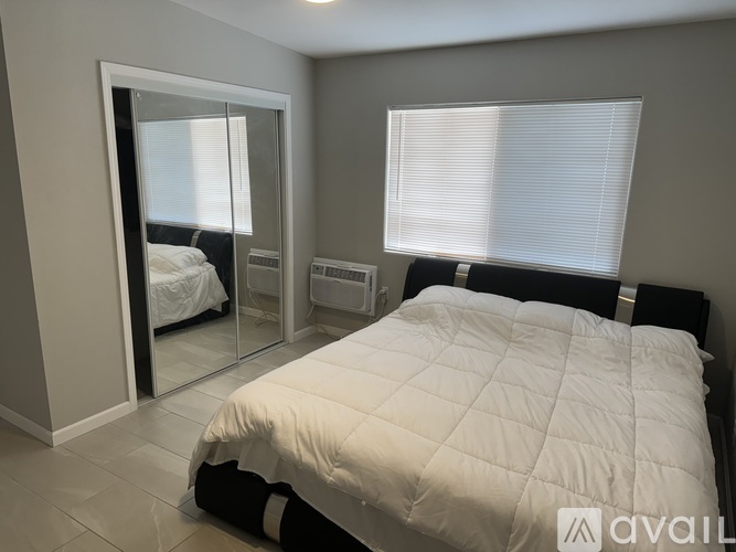 A bedroom with a large bed and a mirror on the wall.