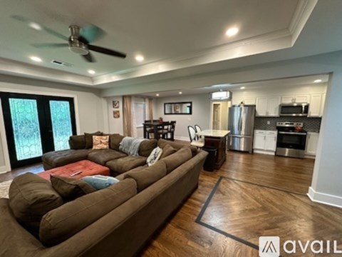 A living room with a brown couch and a ceiling fan.