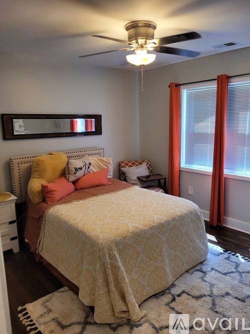A bedroom with a bed covered in a yellow comforter and a ceiling fan above it.