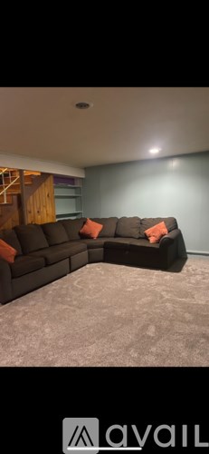 A living room with a grey carpet and a black sofa.