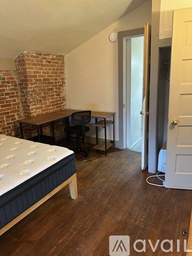 A bedroom with a brick wall and a bed.