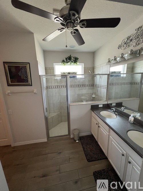 A bathroom with a glass shower stall and a ceiling fan.