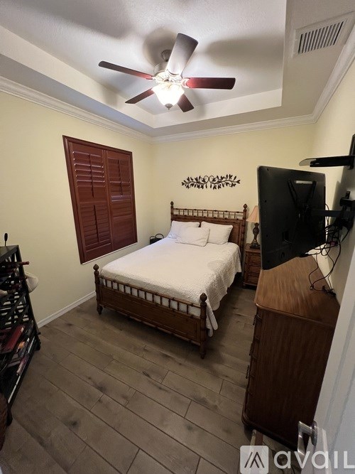 A bedroom with a bed, a television, and a ceiling fan.