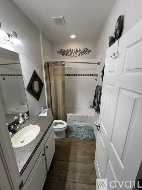 A bathroom with a toilet, sink, and mirror.