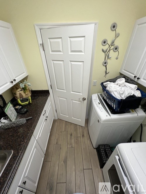 A white door is in a kitchen with a washing machine under it.