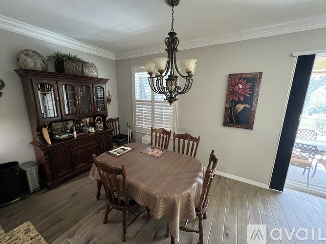 A dining room with a table set for four and a chandelier hanging from the ceiling.