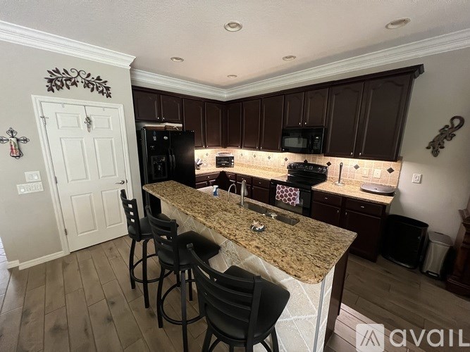 A kitchen with a granite countertop and black chairs.