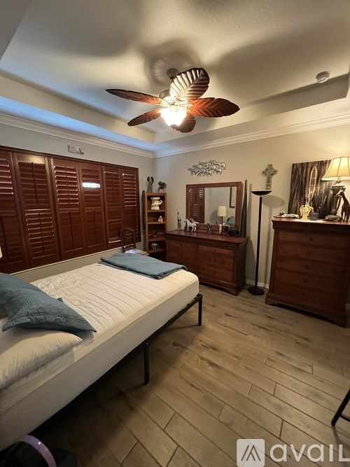 A bedroom with a bed, a dresser, and a ceiling fan.