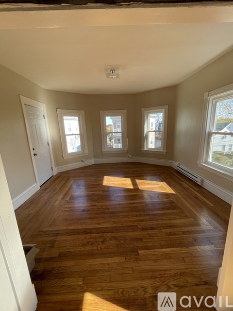 A room with wooden floors and three windows.