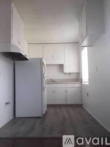 A kitchen with white cabinets and a refrigerator.