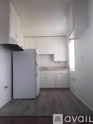 A kitchen with white cabinets and a refrigerator.