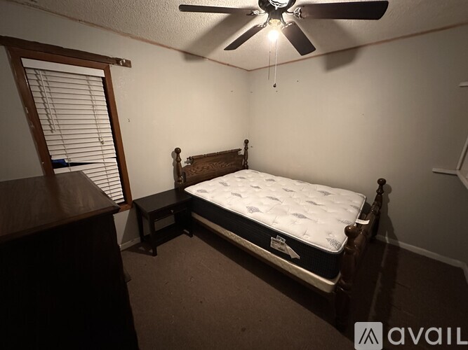 A bedroom with a bed, dresser, and window with blinds.