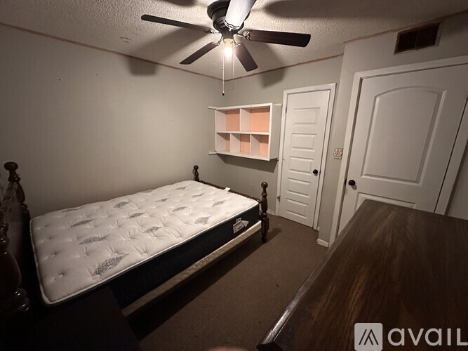A bedroom with a bed, a ceiling fan, and two doors.