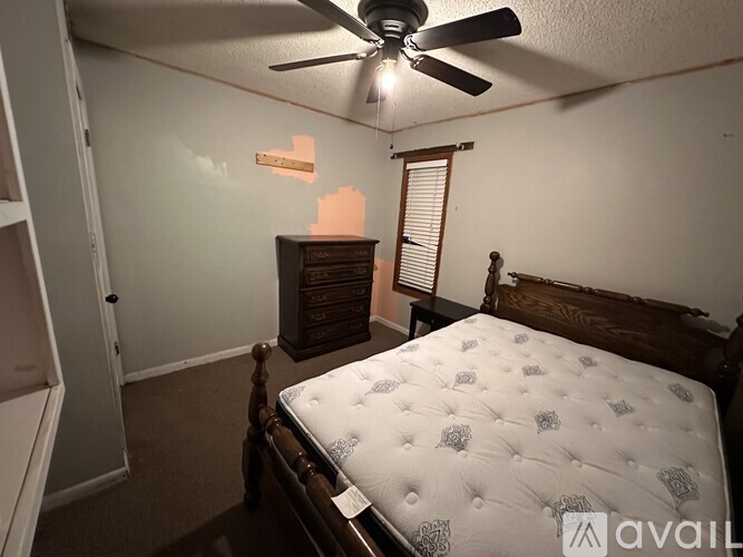 A bedroom with a bed, dresser, and a ceiling fan.