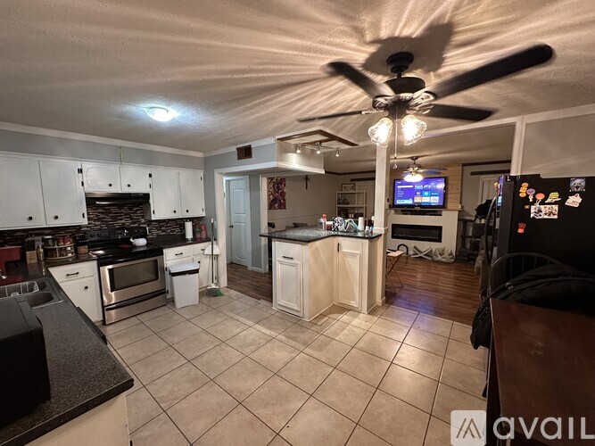A kitchen with a fan and a TV on the wall.